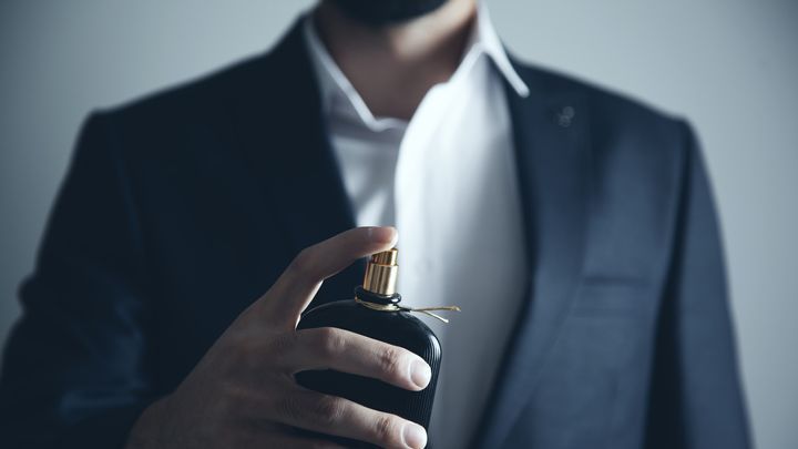 Handsome young man using perfume