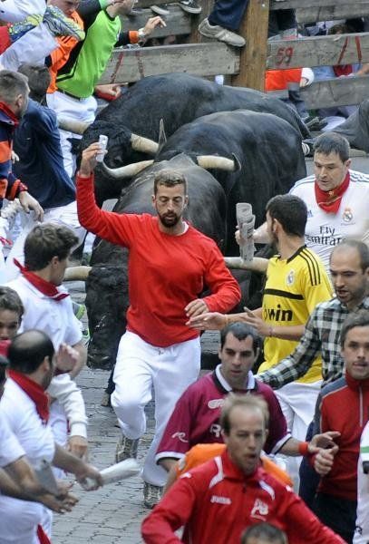 A participant runs in front of Jandilla's bulls as he takes a selfie during the fifth bullrun of the San Fermin...