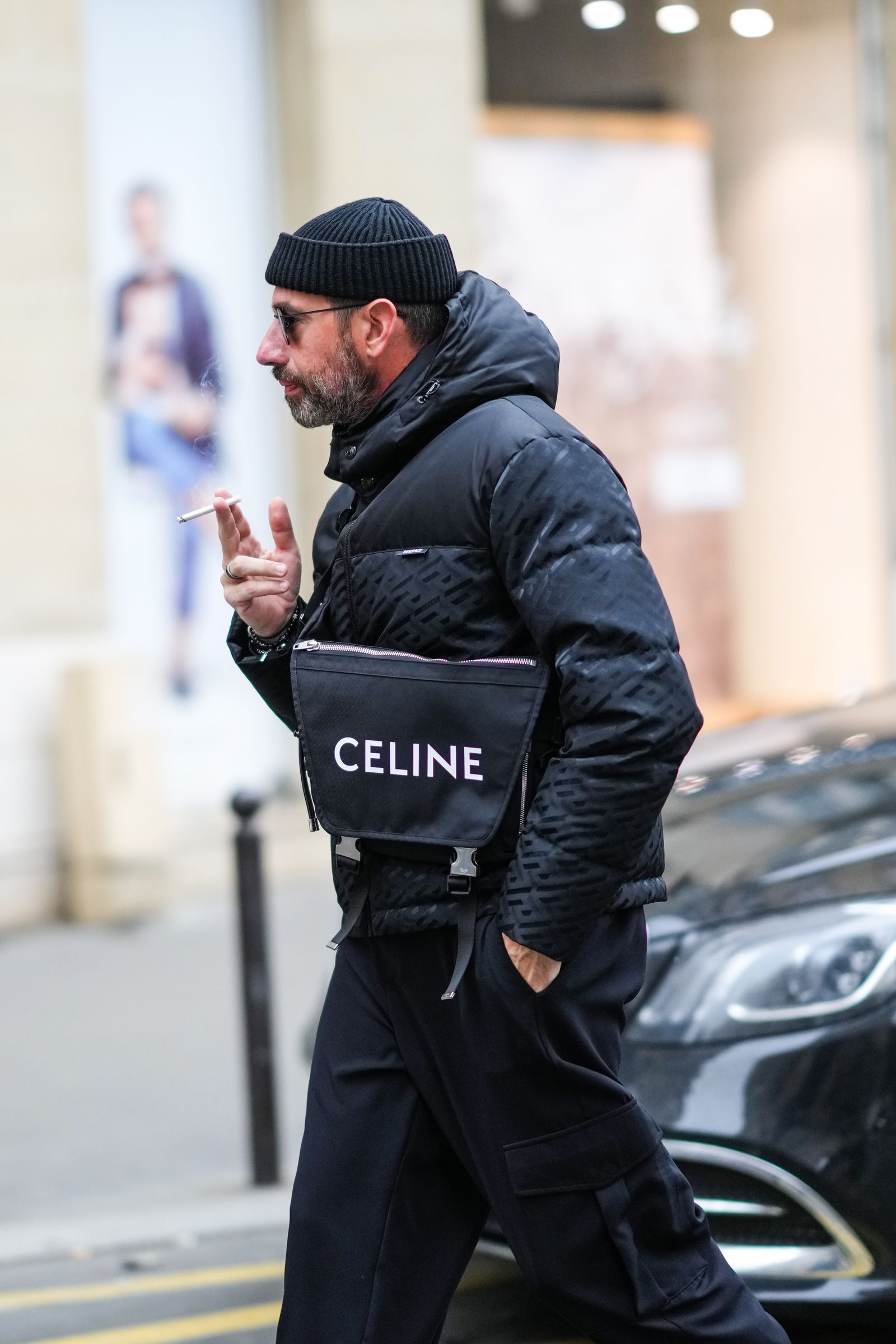 PARIS FRANCE JANUARY 23 A guest wears black sunglasses a black ribbed wool beanie a black print pattern hoodie puffer...