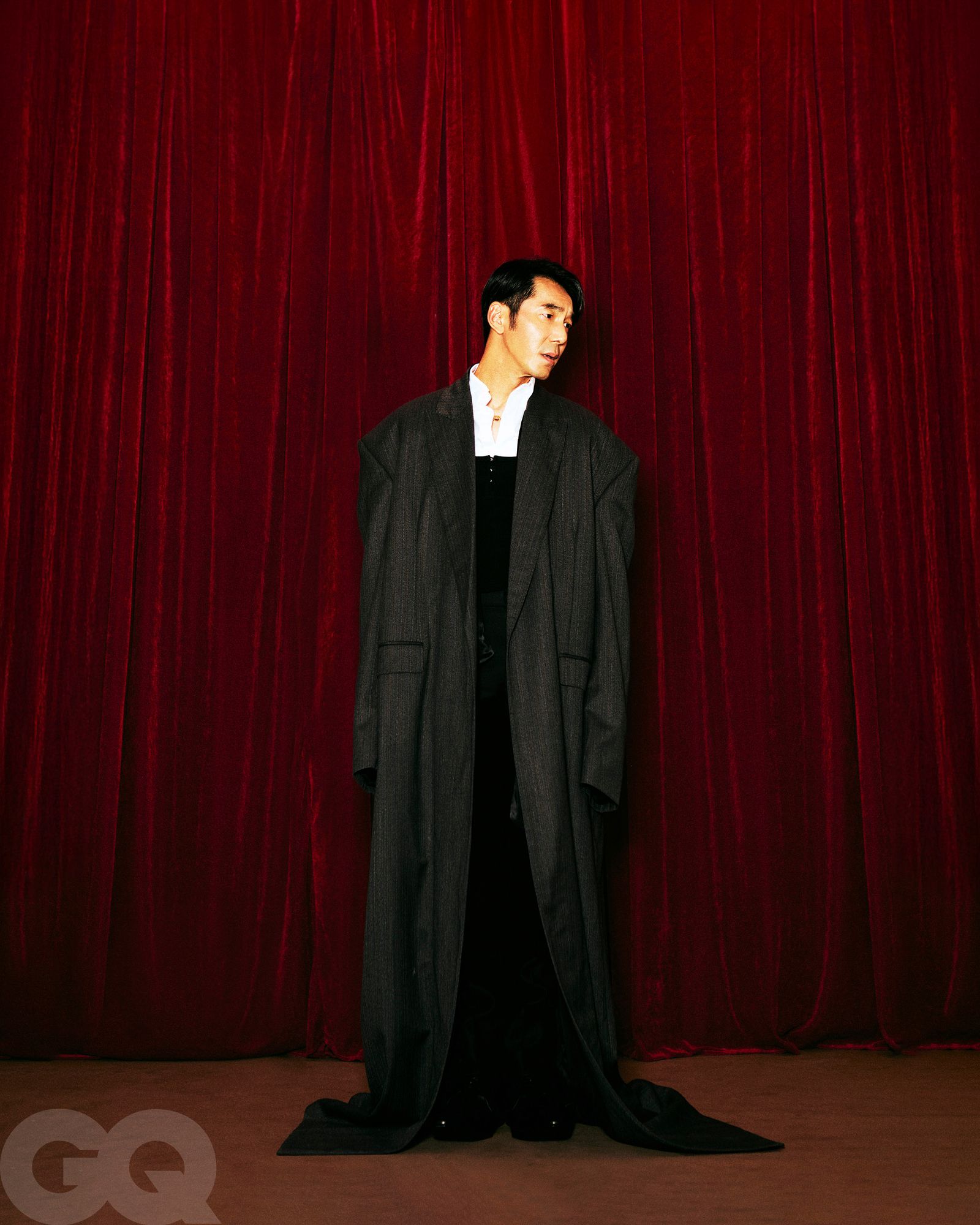深灰色長大衣、尖頭皮鞋,都是Balenciaga。Loewe黑色西裝褲。Louis Vuitton紅寶石珍珠項鍊。白色襯衫、黑色背心、緞面綁帶,造型師私物。