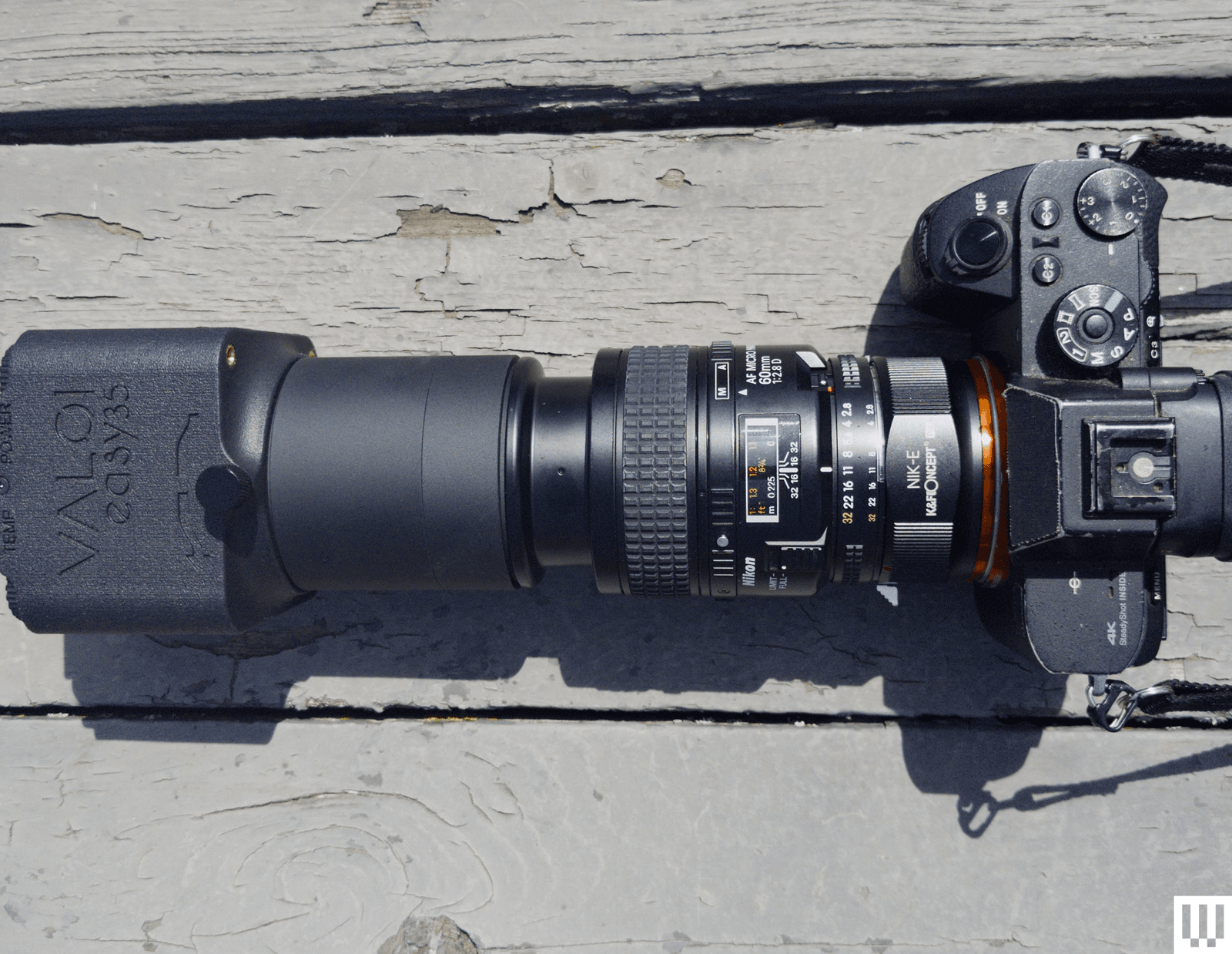 Overhead view of a digital camera with a long black lens attachment connected to a small black plastic box