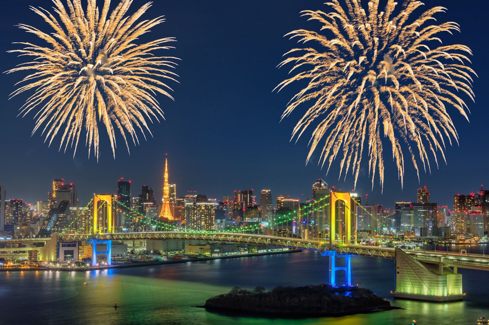 Colorful display of fireworks above the Rainbow Bridge in Tokyo Japan. Waterfront in Shibaura a district of Minato...