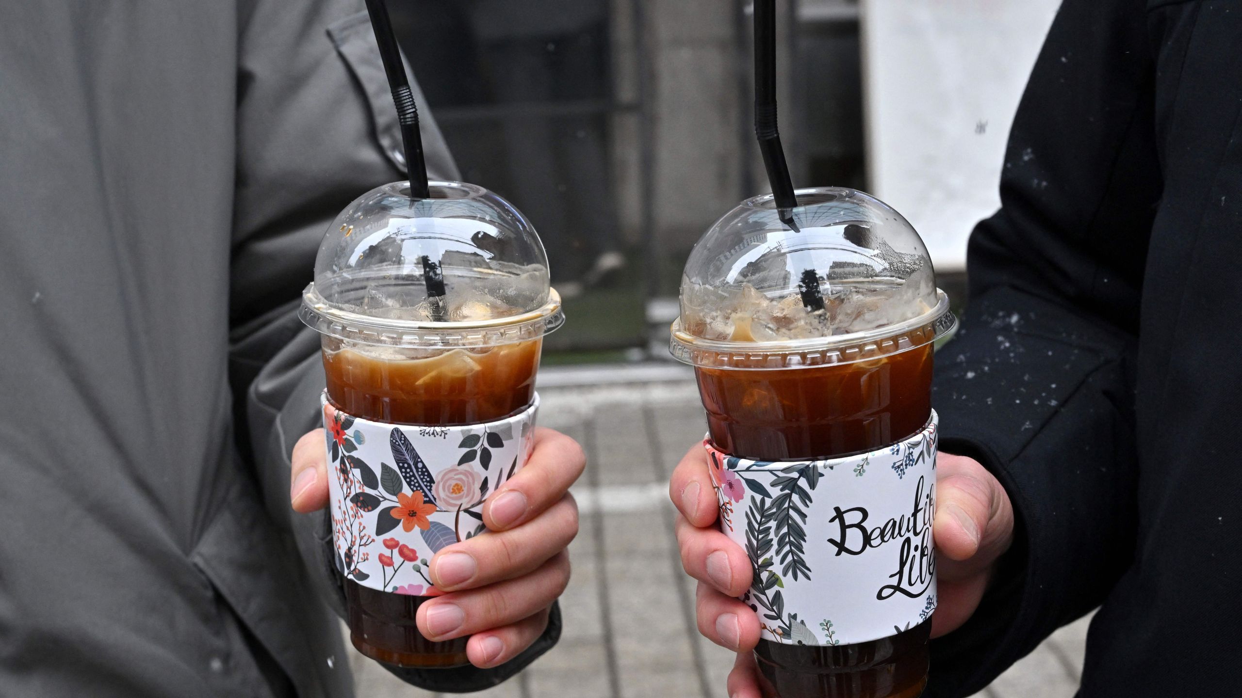 This picture taken on January 26 2023 shows people holding iced Americanos during an interview with AFP on a street in...